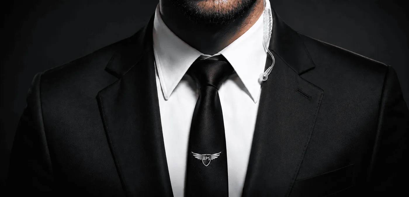 Agent de sécurité en costume sombre et cravate au logo Angel Protection, oreillette de radio à l’oreille